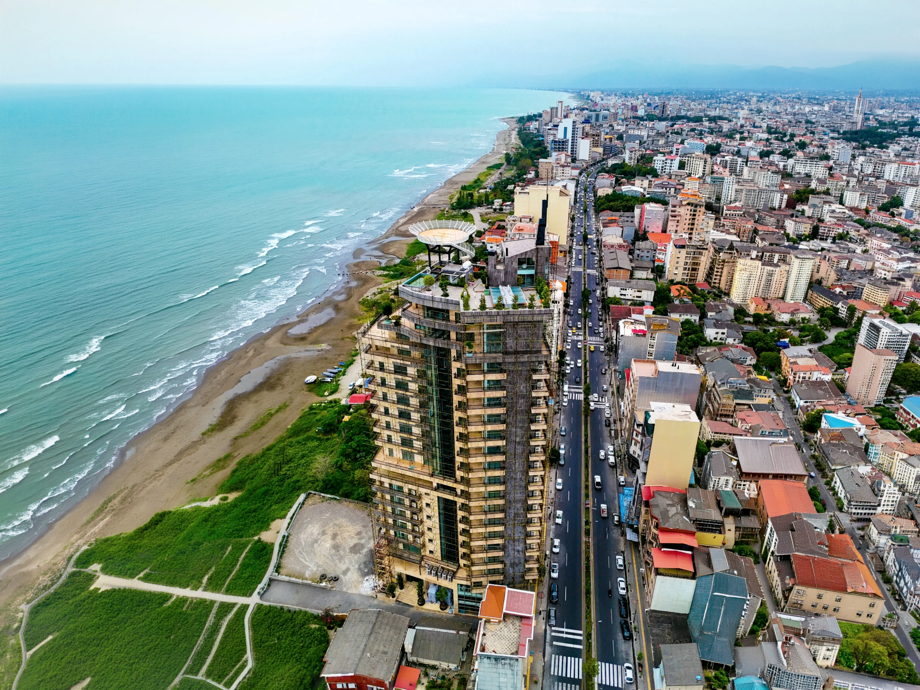 The tower at the water's edge seen from the air, the town behind it and the beach running away up the coast