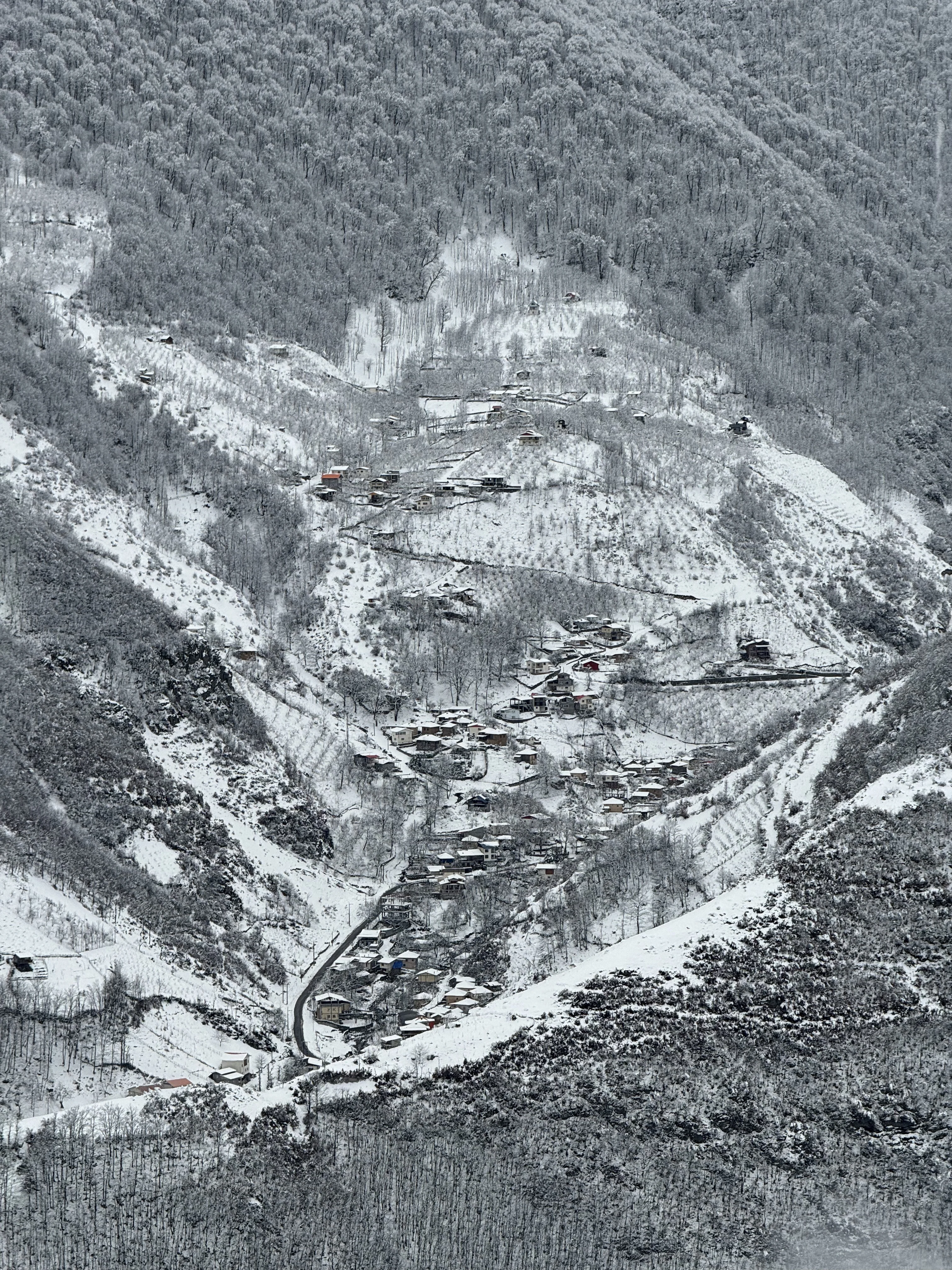 A village on a slope above the valley floor under snow