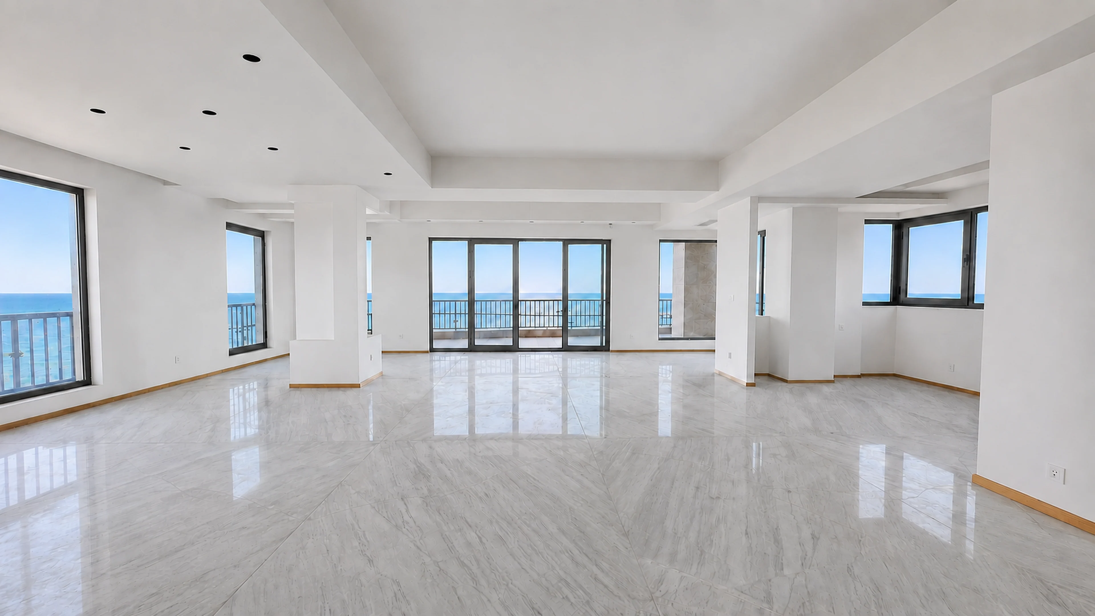 Open reception room, polished marble underfoot, sliding doors onto a sea-facing balcony